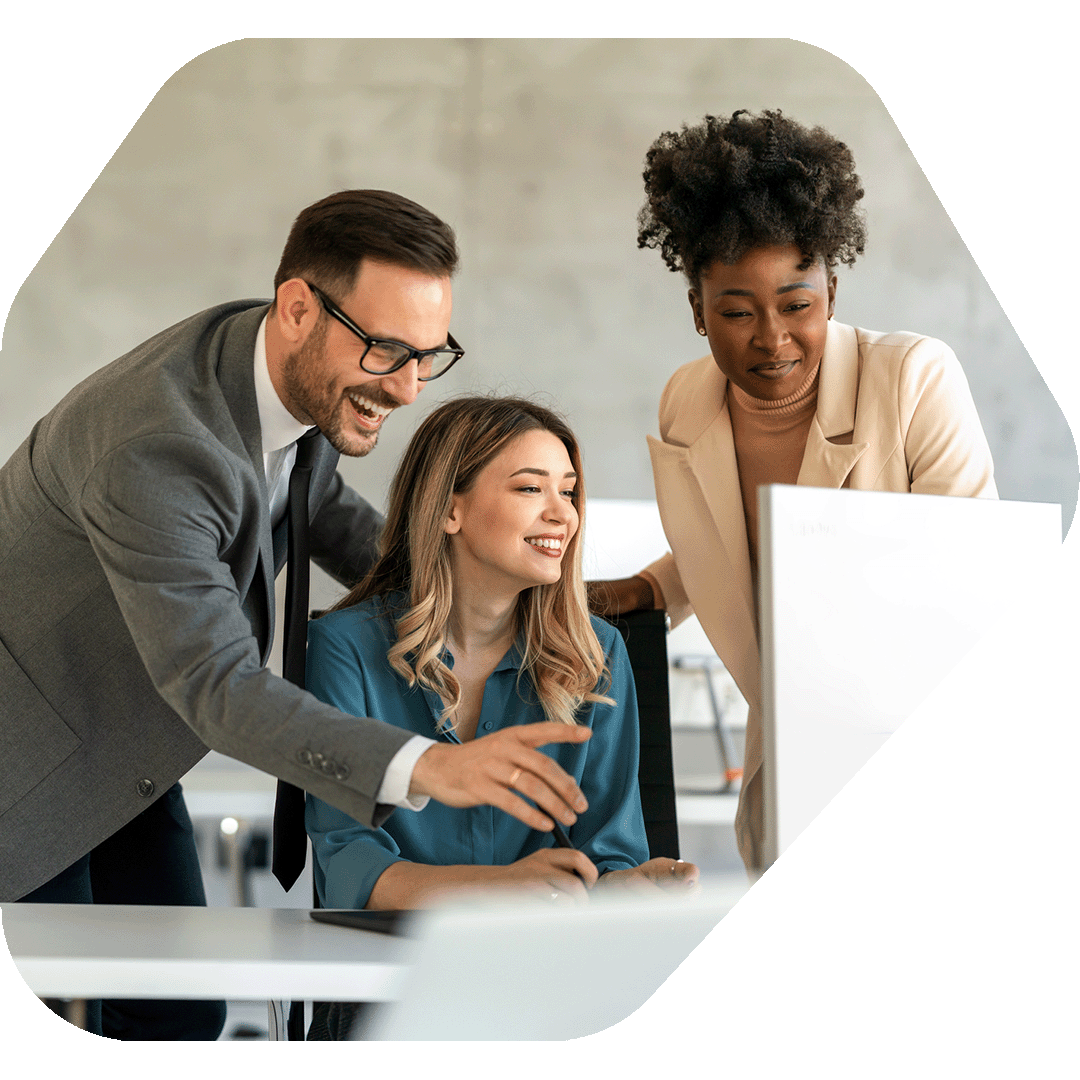 Two co-workers look at a laptop and smile